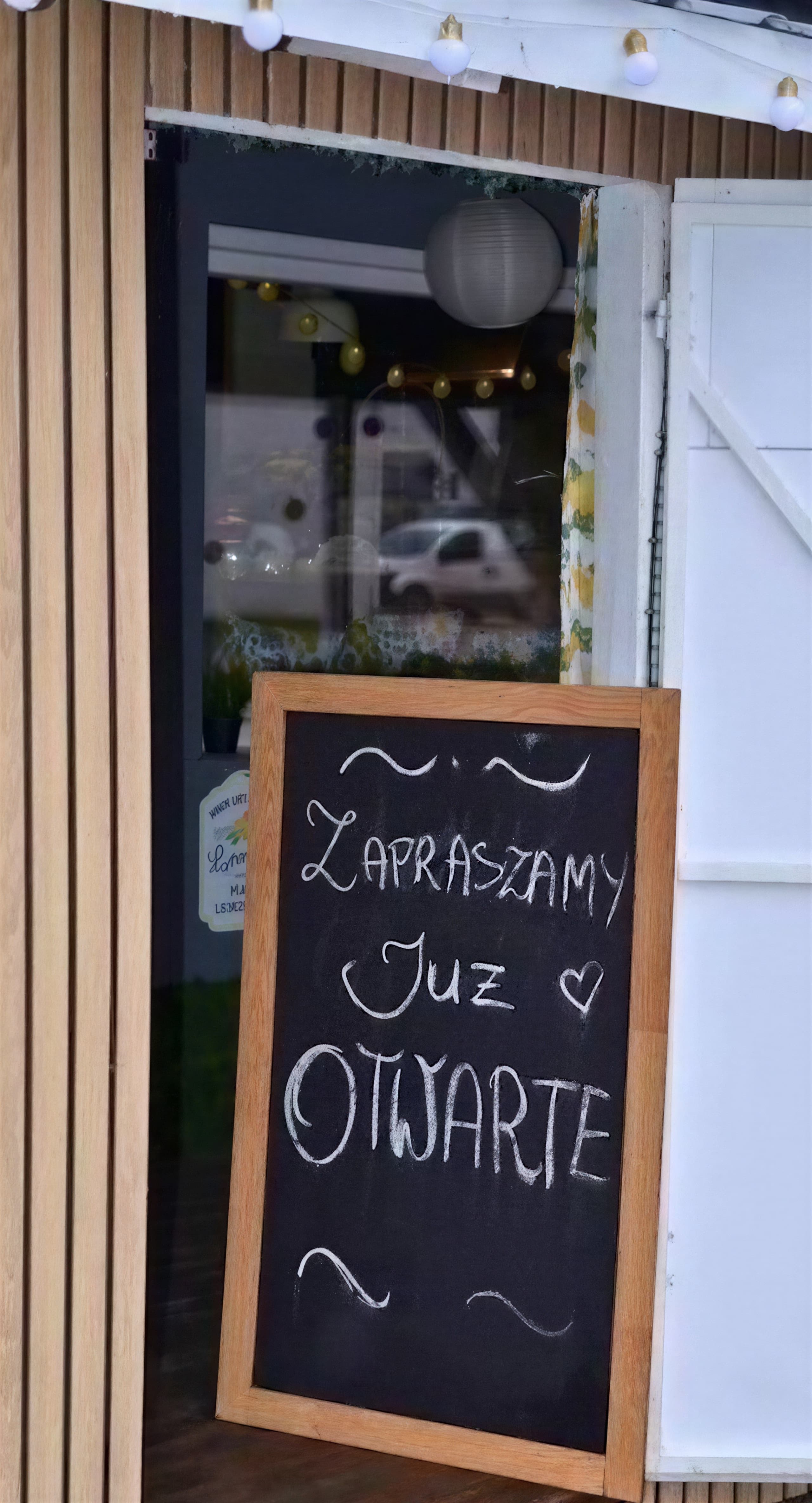Wejście do Bistro Mr. Rollo z tablicą Zapraszamy, już otwarte
